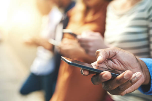 Close-up of diverse hands holding and using smartphones, illustrating the mobile app development process.